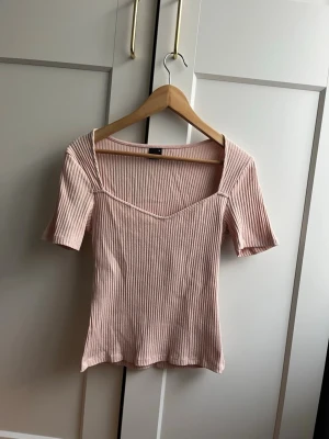 Ljusrosa ribbad topp med v-ringning - Babyrosa ribbad topp med v-ringad hals och korta ärmar💕 Toppen är från Gina Tricot i storlek M, mycket fint skick✨