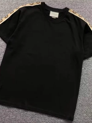 Svart Gusi t-shirt med beige band - Snygg svart t-shirt från Gusi med beige band och logga längs axlarna. Klassisk rund halsringning och korta ärmar. Perfekt för dig som vill ha en stilren men ändå lyxig look.