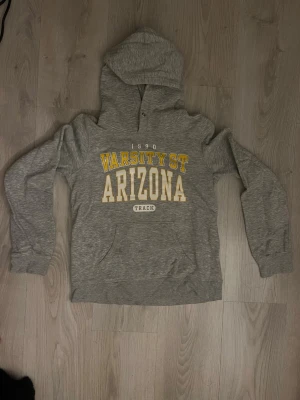 Grå hoodie   - Grå hoodie från H&M med tryck i gult och vitt.