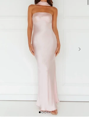 Ljusrosa axelbandslös långklänning - Elegant axelbandslös långklänning i ljusrosa satinliknande material. Aldrig använd och har prislappen kvar.