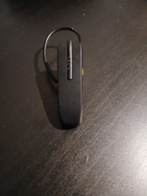 Jabra Bluetooth headset svart/gul - Snyggt och smidigt Bluetooth-headset från Jabra i svart plast med gul detalj runt öronsnäckan. Utrustad med öronkrok för säker passform och enkel knapp på framsidan. Perfekt för handsfree-samtal och trådlös frihet.