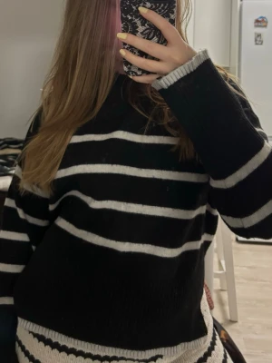 Randig svartvit stickad tröja - Säljer en svart stickad tröja från Bershka med vita horisontella ränder. Tröjan har en relaxed fit, långa ärmar och ribbade muddar vid ärmslut och nederkant. Perfekt för dig som gillar en enkel men snygg look.