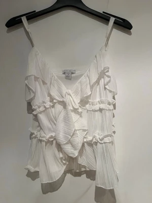 Två stycken linnetoppar  - Säljer två söta linnetoppar från Amisu med tunna axelband, volanger och knyt fram. Den ena är vit och den andra beige. Vita i storlek M och den andra i storlek S aldrig använda 