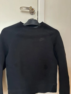 Svart sweatshirt från Nike - Säljer en svart sweatshirt från Nike med diskret logga på bröstet. Tröjan har rund halsringning och långa ärmar. Perfekt för en sportig och avslappnad stil. Tillverkad i mjukt bomullsmaterial.