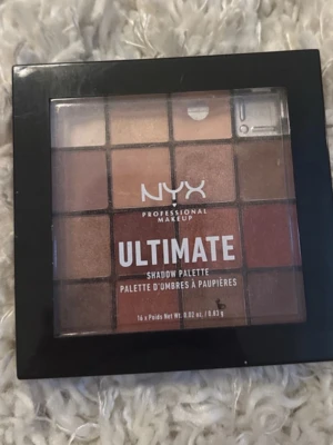 NYX Ultimate Shadow Palette Warm Neutrals - NYX Ultimate Shadow Palette Warm Neutrals har 16 ögonskuggor i varma toner som beige, brunt, guld och koppar. Fyrkantig palett i svart plast med genomskinligt lock. Perfekt för dig som gillar naturliga och jordnära färger.