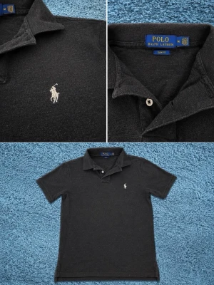 Svart pikétröja från Polo Ralph Lauren - Klassisk svart pikétröja från Polo Ralph Lauren med vit broderad logga på bröstet. Tröjan har krage, knappar vid halsen och korta ärmar. Slim fit-modell i mjuk bomull som passar perfekt till jeans eller shorts. Storlek S/M