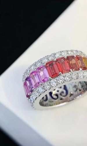 Vit guld ring  med färgglada stenar - Unik vit guld  med  lab odlade  stenar i regnbågens färger, från gult och orange till rosa och lila. Ringen är dekorerad med gnistrande klara stenar runt hela bandet och har en elegant, bred design. Perfekt för dig som vill sticka ut med färg och glitter. 