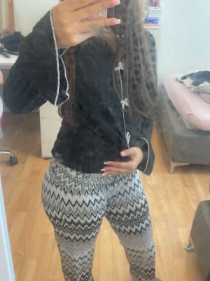 Mönstrade zigzag leggings i svartvitt - Säljer ett par snygga leggings med svartvitt zigzag-mönster. De har hög midja och är stretchiga för en bekväm passform. Perfekta för dig som gillar att sticka ut med coola mönster. Materialet känns mjukt och följsamt.