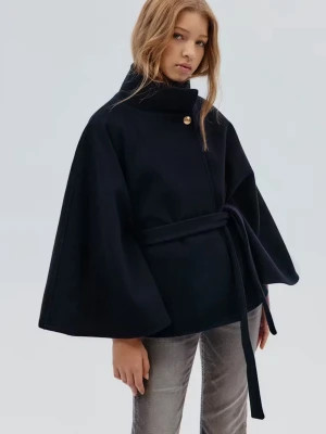 Svart cape-kappa med bälte - Stilren svart cape-kappa med hög krage och ett dekorativt guldknapp vid halsen. Kappan har vida ärmar och knyts i midjan med ett matchande tygbälte. Använd ett fåtal gånger och den är i storlek 12-14Y men den passar mig som har XS 