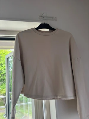 Sweatshirt Nelly - Kortare beige sweatshirt från Nelly med stora armar i storlek S!