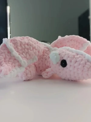 Rosa virkad drake - Söt handvirkad drake i mjukt, fluffigt garn. Färgen är ljusrosa med vita detaljer och svarta ögon i plast. Perfekt som dekoration eller gosedjur till någon som gillar unika och gulliga prylar.