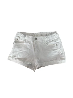 Vita denimshorts med fickor - Snygga vita shorts i denim med klassisk femficksdesign och knappgylf. Shortsen har uppvikta benslut och bälteshällor i midjan. Perfekta för varma dagar och enkla att matcha med olika stilar. Storlek 164 men passar även mig som bär XS