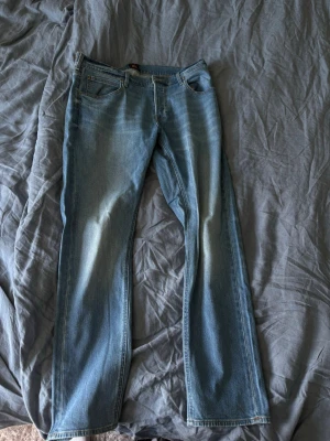 Ljusblå raka jeans från Lee - Säljer ett par ljusblå jeans från Lee med klassisk femficksdesign och raka ben. Jeansen har en snygg tvätt och Lee-logga på bakfickan. Perfekta för en avslappnad och trendig look.