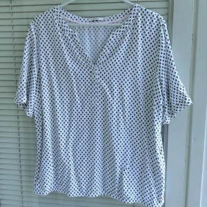 Mönstrad Cecil blus,M - Vit blus med svart mönster från Cecil. Blusen har en v-ringning och korta ärmar som upprullbara. Passar bra för en avslappnad men ändå stilren look. 100% viskos.  Storlek M.  Från armhålan till armhålan 56cm, längd 61cm. Knappt använd.