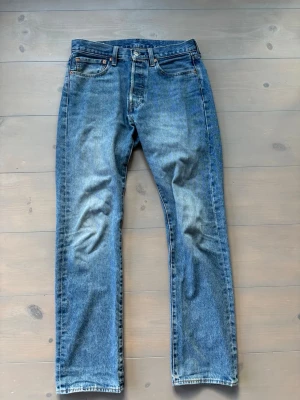 Levi's blå raka jeans - Klassiska blå Levi's jeans med rak passform och fem fickor. Jeansen har en snygg tvättad look och är tillverkade i slitstark denim. Perfekta för en avslappnad och tidlös stil. Stängs med knappgylf och har Levi's ikoniska läderpatch bak.