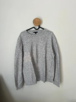 Gråmelerad stickad tröja från COS - Säljer en stilren gråmelerad stickad tröja från COS. Tröjan har rund halsringning, långa ärmar och är tillverkad i ett mjukt material som passar perfekt för kyligare dagar. Enkel och clean design som funkar till det mesta.