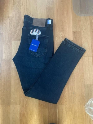 Mörkblå jeans från Jacob Cohen - Skicka bud! Är i behov av pengar de bensin kostar mycket. Grisch jeans Snygga mörkblå jeans från Jacob Cohen med klassisk femficksmodell och raka ben. Jeansen har silverfärgade knappar, patch i mocka baktill och kommer med en liten tygpåse. Tillverkade i mjuk denim med exklusiv känsla.