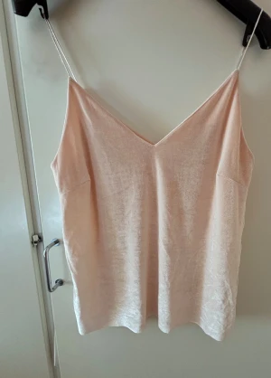 Lnnetopp Gina Tricot - Säljer denna fina toppen från Gina Tricot i mjuk sammet. Toppen har smala axelband och v-ringning framtill. Perfekt till sommarens alla tillfällen och ger en lyxig känsla med sitt glansiga material. Använd några gånger.