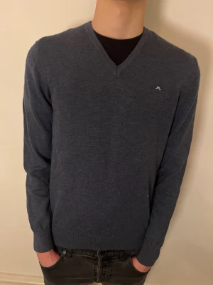 Blå V-ringad tröja J.Lindeberg - Säljer min oanvända J.Lindberg sweatshirt. Tröjan är i merinoull och har en bra passform. Jag på bilden är 184cm och väger 70kg.  Hör av dig vid frågor och funderingar!