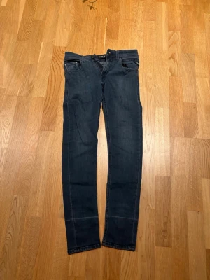 Mörkblå slim fit jeans från Replay - Snygga mörkblå slim fit jeans från Replay med klassisk femficksdesign och diskreta slitningar. Jeansen har raka ben och är tillverkade i stretchigt denimtyg för extra komfort. Perfekta för en trendig och avslappnad stil. Passar dig bäst vid 160-165cm lång. HÖR AV DIG VID FÖNDERING!