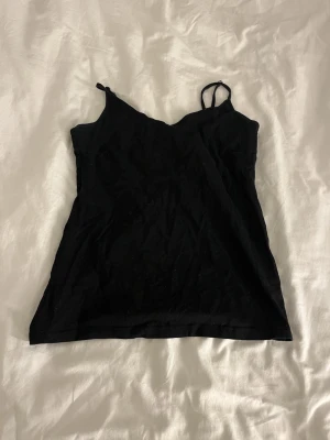 Svart linnetopp med smala axelband - Snygg svart linnetopp med tunna axelband och enkel design. 