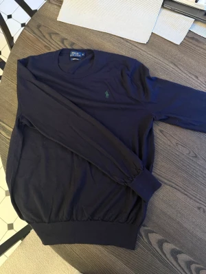 Marinblå Polo Ralph Lauren merino, passar S/M - Marinblå merino knitwear stickad tröja från polo Ralph lauren med mörkgrön häst. Storlek är XL men den passar snarare S/M. Jag är 175 och den passar mig bra. Skicket är mycket bra, inget synligt slitage.     Tröjan är i 100% merinoull. Priset är inte hugget i sten. Hör av dig vid frågor! Kan sänka pris vid snabb affär