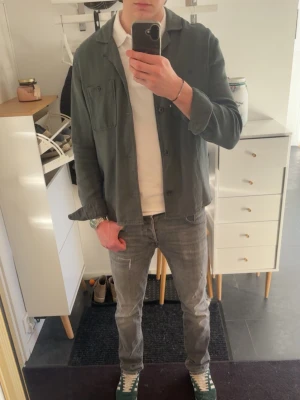 Mörkgrön overshirt  - Stilren mörkgrön overshirt med klassisk krage och knappar framtill. Skjortan har två bröstfickor och en relaxed, loose passform som passar perfekt över en t-shirt. Enkel och clean look för dig som gillar minimalistisk stil.