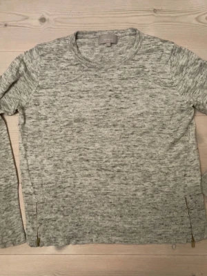 Gråmelerad tröja med dragkedjor från Inwear - Snygg gråmelerad tröja med rund hals och långa ärmar. Tröjan har ribbade muddar och coola guldfärgade dragkedjor i sidorna nedtill. Perfekt till jeans eller kjol för en avslappnad look.