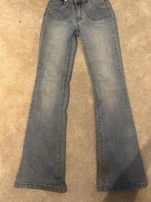 Blå bootcut jeans från Abrand Jeans - Säljer ett par ljusblå bootcut jeans från Abrand Jeans. Jeansen har hög midja, klassiska fem fickor och en snygg tvättad look. Materialet är denim i bomull och passformen är utsvängd nedtill för en trendig siluett.