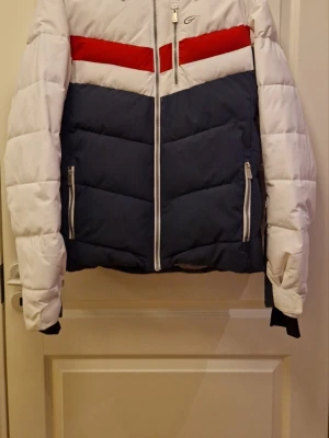 Vit och marinblå pufferjacka - Snygg skidjacka från Everest i vitt och marinblått med röd detalj över bröstet. Kommer från rök-djurfritthem