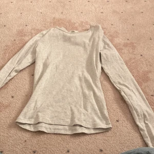 Grå långärmad topp från Gina Tricot - En enkel och stilren grå långärmad topp från Gina Tricot. Modellen är rak med rund halsringning och tillverkad i mjukt material som passar perfekt till alla outfits.