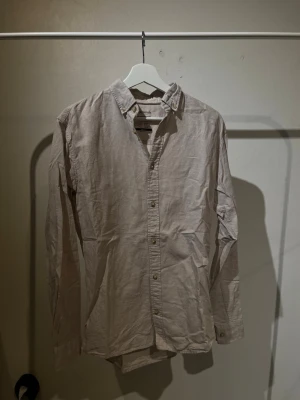 Skjorta - Klassisk beige skjorta, lite linne aktig med knappar framtill och button down-krage. Tillverkad i ett lätt bomullstyg som passar perfekt för varmare dagar. Enkel och stilren design som funkar till många olika looks. perfekt till sommaren!