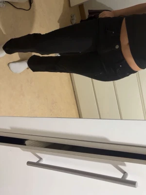 Svarta raka jeans med låg midja - Säljer ett par svarta jeans med rak passform och låg midja. Jeansen har klassisk femficksdesign och stängs med knapp och dragkedja. Perfekta till en enkel topp eller hoodie för en clean look. De är även lite korta på mig och är ungefär 165