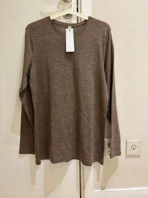  Ny Brun merinoulltröja från Lindex - Säljer en stilren brun långärmad tröja från Lindex Premium i mjuk merinoull. Tröjan har rund halsringning och en enkel, klassisk design som passar perfekt till lager-på-lager under kyliga dagar.