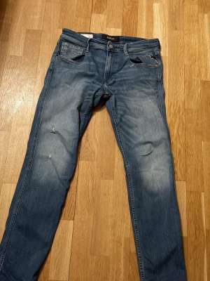 Replay jeans - Snygga blå slim fit jeans från Replay med klassisk femficksdesign och slitningar på låret. Jeansen har en något tvättad look och raka ben. Perfekta för en avslappnad och trendig stil.