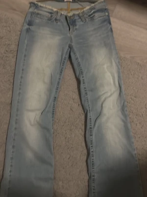 Ljusblå bootcut jeans från Only - Säljer ett par ljusblå bootcut jeans från Only med slitna detaljer och fransad midja. Jeansen har klassisk femficksmodell och är tillverkade i denim med en snygg tvättad look. Perfekta för en avslappnad och trendig stil.