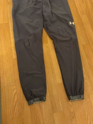 Under Armour blå byxor - Blå träningsbyxor från Under Armour i bra skick. Resår i midjan och benslut. Det finns ett litet hål vid knät (se bild). Annars i fint skick.  