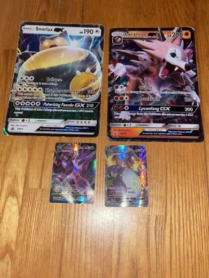 Pokémon jumbo- och vanliga samlarkort - Fyra Pokémon samlarkort, två i jumboformat och två i standardstorlek. Motiven är Snorlax, Lycanroc, Eternatus VMAX och Charizard VMAX. Korten har färgstarka holografiska effekter och är tillverkade i laminerad papp. Perfekt för samlare eller Pokémon-fans.