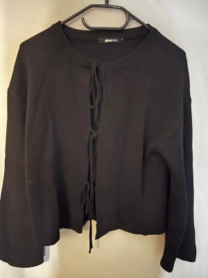 Svart knytkofta från Gina Tricot - Trendig svart kofta från Gina Tricot med knytning framtill. Perfekt att styla över ett linne eller t-shirt för en cool lager-på-lager-look. Är inte alls mycket använd.