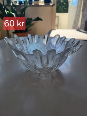 Dekorativ glasskål i vågig form - Säljer en unik och dekorativ glasskål med vågig kant och frostad yta. Skålen är genomskinlig och har ett mönster i botten som ger ett coolt ljusspel. Perfekt som fruktskål eller till snacks på bordet.