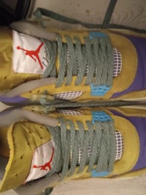 Air Jordan 4 Retro Union LA sneakers - Färgglada Air Jordan 4 Retro Union LA sneakers med mesh och mockadetaljer i gult, lila och blått. Skorna har gröna skosnören, vit mesh på tån och blåa plastdetaljer vid snörningen. Klassisk Jumpman-logga på plösen och AIR JORDAN-märke på insidan.