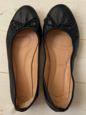 Svarta ballerinaskor med rosett - Söta ballerina skor, knappt använda och sulan inuti är mycket fräsch. Stl 40 men aningen små så skulle kanske passa någon med storlek 39❤️