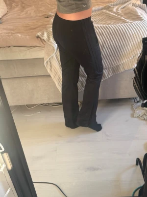 Svarta adidas-leggings - Säljer ett par svarta vintage leggings med bootcut. De har en diskret broderad krona på höften. De har dragkedjefickor på sidorna och är tillverkade i stretchigt material som sitter bekvämt. Perfekta för dig som gillar stilrena och funktionella leggings. Low waist. Finns ett litet hål på ena knäet men tror det är lätt att fixa. Jag är 178 cm. 