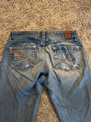 Blå bootcut jeans  - Säljer ett par blå bootcut jeans från Replay med snygga flickor. Midjemått: 37 cm. Innerbenslängd: 79 cm