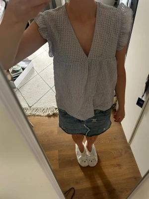 Ljuslilablå blus med volangärm - Supersöt ljuslila blus med volangdetaljer vid ärmarna. Djup V-ringning framtill och luftig passform. Perfekt till jeans eller kjol för en trendig look. Materialet känns lätt och andas bra.