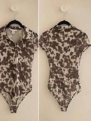 Brunmönstrad mesh body  - Trendig body i meshmaterial med brun och beige batikmönster. Modellen har korta ärmar, krage och dragkedja framtill samt knäppning i grenen. Perfekt för dig som gillar statement-plagg och vill sticka ut lite extra.