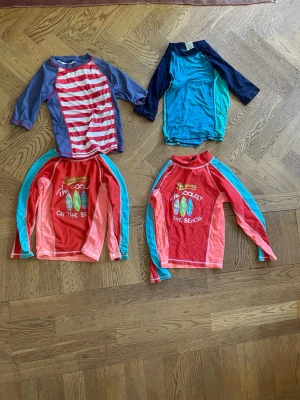 Badkläder barn - Rosa badbyxor storlek 110-116.  Svarta badbyxor storlek 150. Har gått sönder lite uppe vid snöret.  Röda badtröjorna passar 4-6 och 6-8 år.  Vit röd randiga bad tröjan storlek 122-128.  Blåa badtröjan storlek 134-140.  Ljus blåa långa badbyxor storlek 122-128.  Mörkblåa långa badbyxor storlek 134-140.
