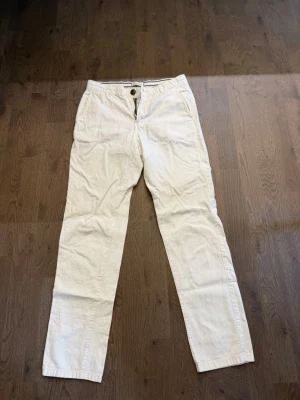 Vita linnebyxor från Selected Homme - Snygga vita linnebyxor från Selected Homme med klassisk rak passform och två sidofickor. Byxorna har en enkel design med knappgylf och är tillverkade i ett mjukt bomullstyg som känns skönt mot huden. Perfekta för en clean och avslappnad stil. W: 29. L: 32