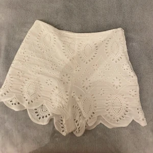 Vita broderade shorts med spetskant - Snygga vita shorts med broderade detaljer och spetskant. De har hög midja och ett unikt mönster med hålbroderi som ger en somrig och fräsch känsla. Perfekta för varma dagar och lätta att matcha med olika toppar. Från Zara och använda ett fåtal gånger🫰. Jag brukar vara S så skulle säga att de passar både S och M!