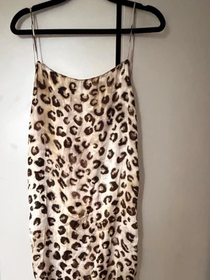 Leopardmönstrad långklänning - Snygg långklänning med leopardmönster och tunna axelband. Klänningen har en slits framtill och är tillverkad i satin material som ger en lyxig känsla. I storlek S från Zara aldrig använd heller